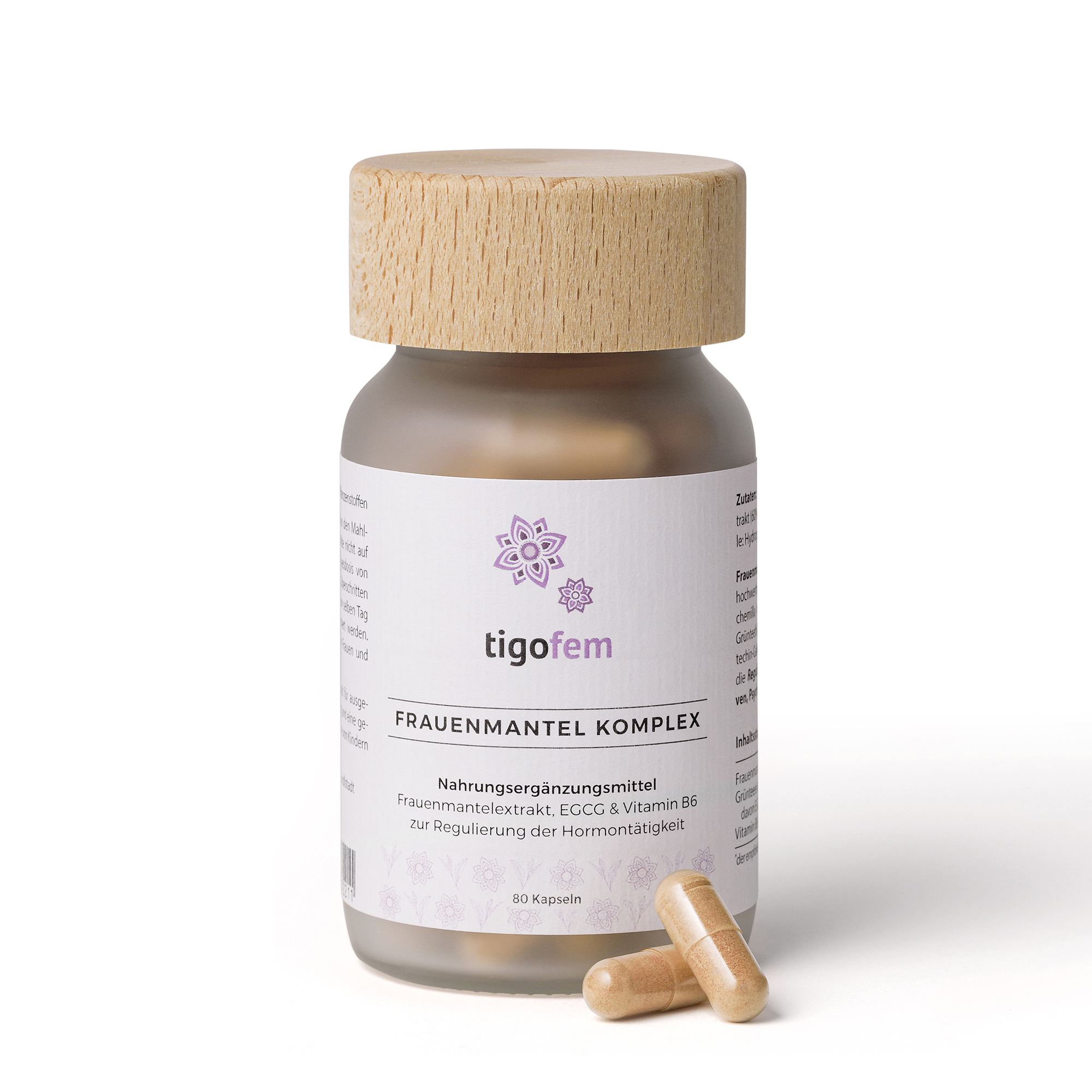 Glasbehälter mit Nahrungsergänzungsmittel "Frauenmantel Komplex" und zwei Kapseln daneben.